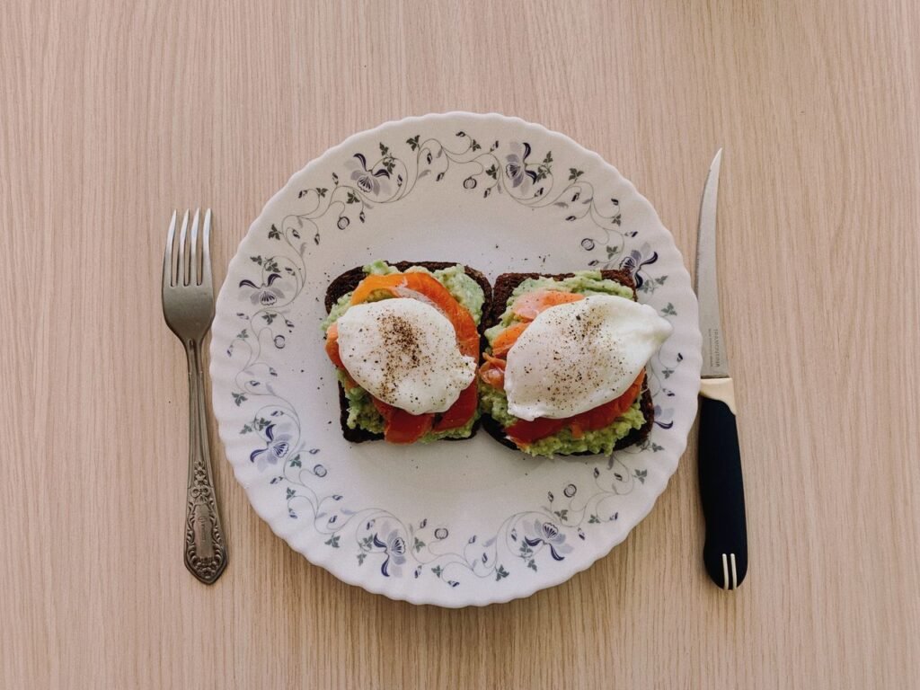 Delicious avocado toast topped with poached eggs and tomatoes, served on a vintage plate. Perfect breakfast idea.