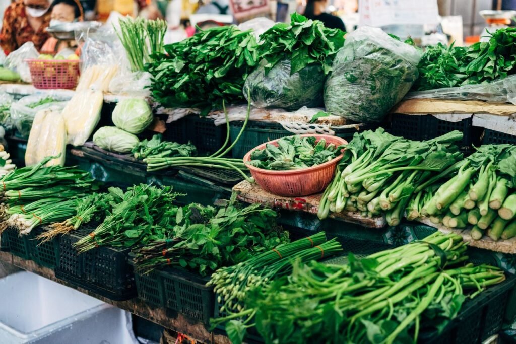 Vibrant display of fresh green vegetables at an outdoor market stall. Ideal for healthy lifestyle themes.