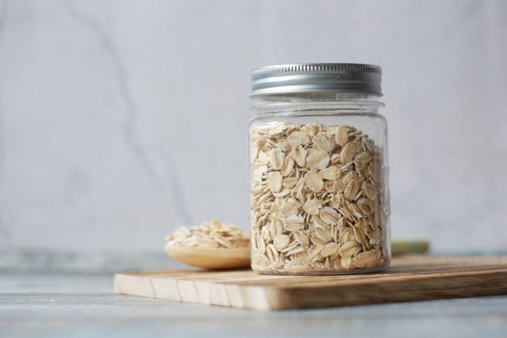 A jar filled with oats sits on a wooden cutting board, showcasing a minimalist kitchen decor.