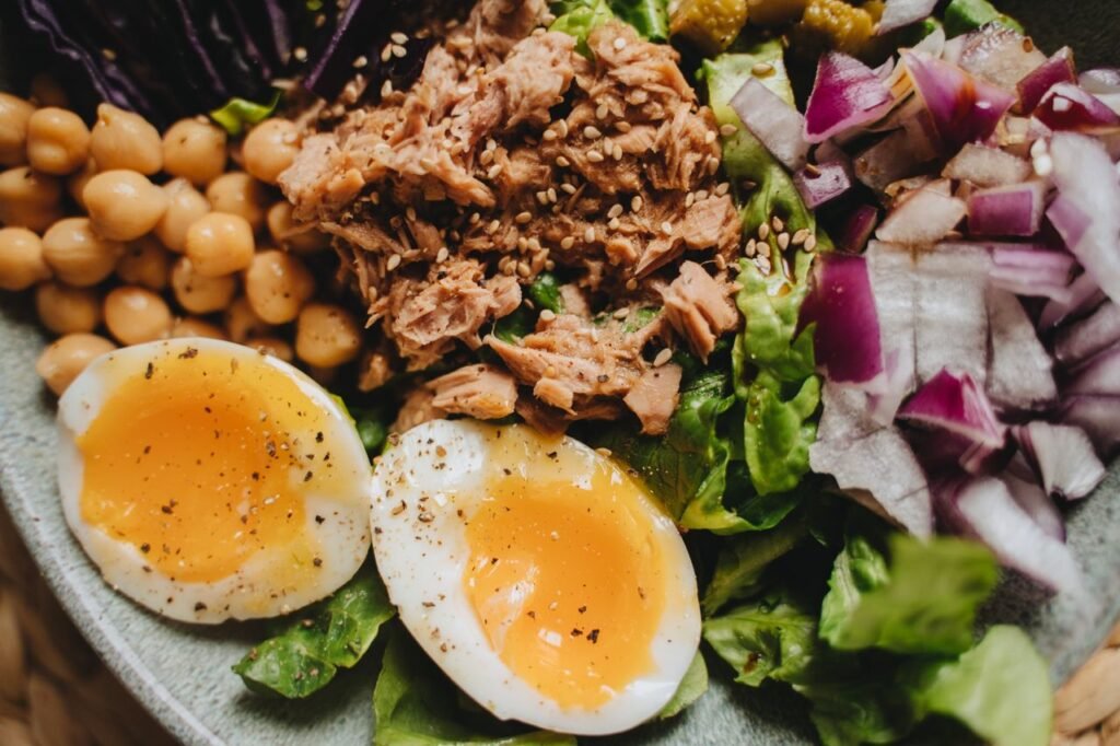 Close-up of a nutritious salad with tuna, soft-boiled eggs, and fresh vegetables.