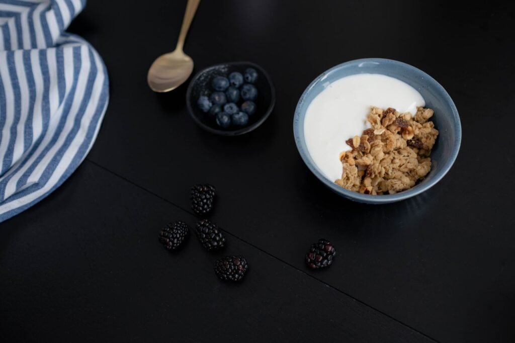 A healthy breakfast bowl with granola, yogurt, blackberries, and blueberries.