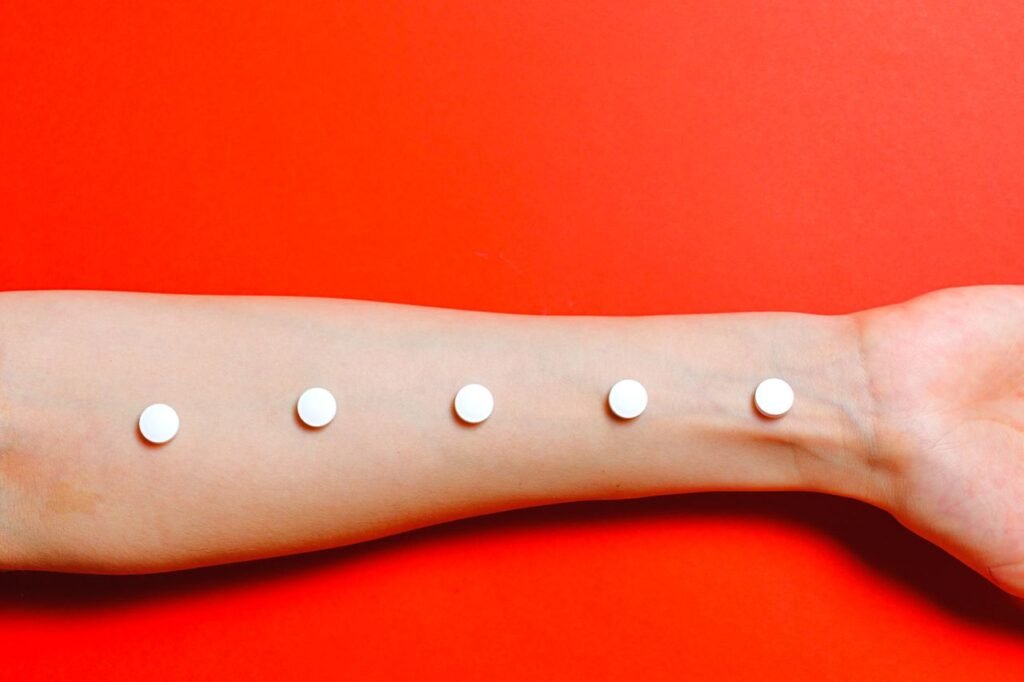 Conceptual image of an arm with pills lined up, set against a vivid red background, symbolizing healthcare themes.