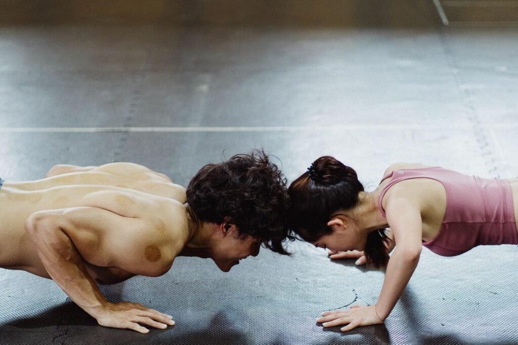 Asian couple performing push-ups together, showcasing fitness and teamwork.